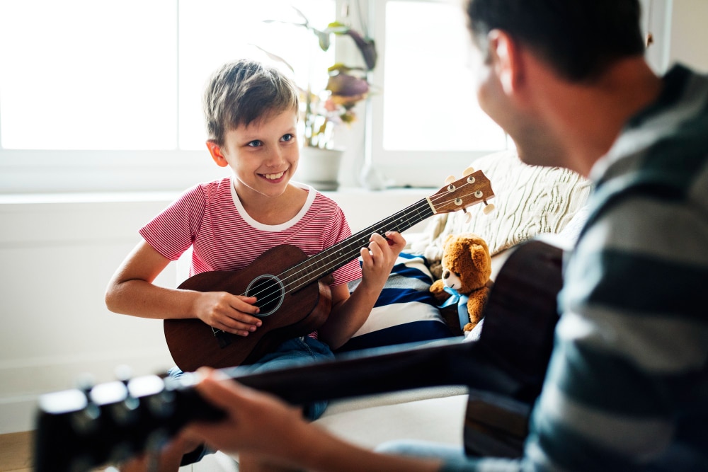 Professeur de guitar offrant un cours de musique à un enfant. L'enfant sourit, car sont prof rend l'apprentissage de la musique amusant.