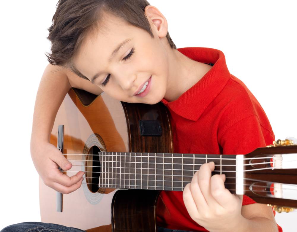 beginner guitar lessons for kids. Boy practising his guitar.