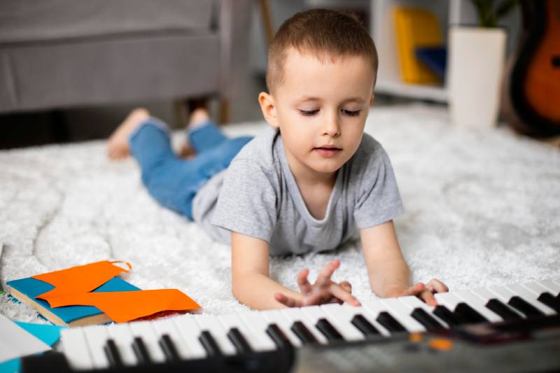 Jeune garçon pratique le piano dans son salon après avoir pris un cours de piano pour enfant chez Musiprof